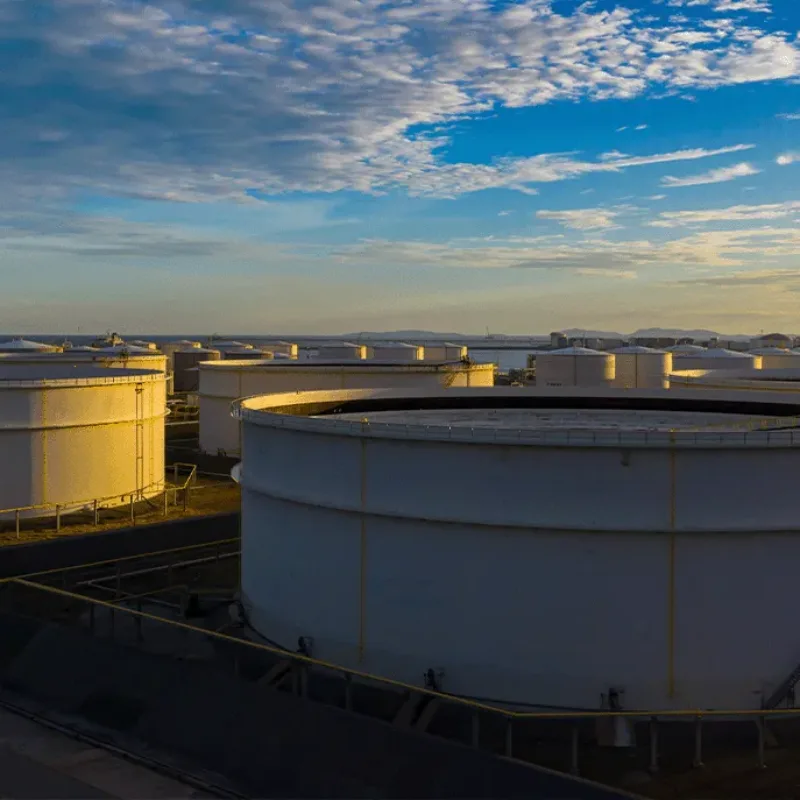 Aerial view of oil storage tanks under a blue sky with scattered clouds